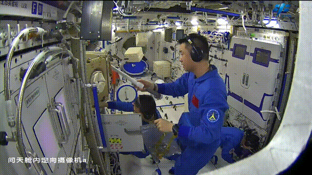 O astronauta Chen Dong usa um coletor de resíduos.